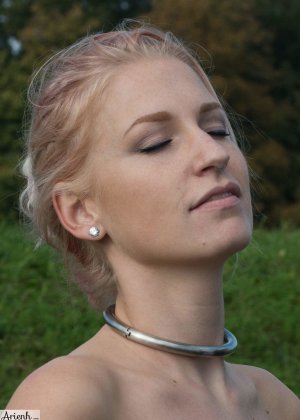 Девушка с воротником Ариен Осень моделирует красный кожаный корсет, находясь в поле