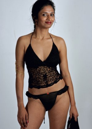 Индийская леди Кавья Шарма сидит на подушке, сняв одежду и ботинки